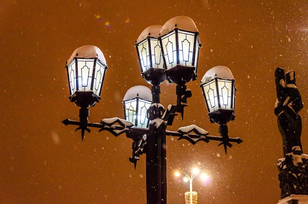 Ein Laternenpfahl mit Lampen in einer Winternacht unter dem Schnee.