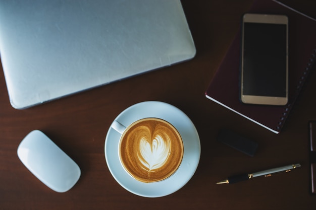 Ein Lattekaffee und ein Laptop auf der Tabelle.