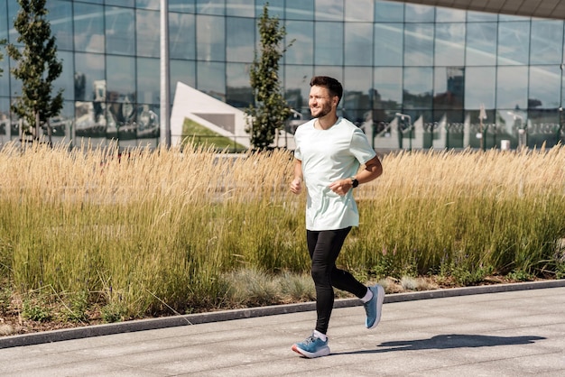 Ein laufender athletischer Mann lächelt einem glücklichen Workout-Mann in Sportbekleidung benutzt die App zum Laufen