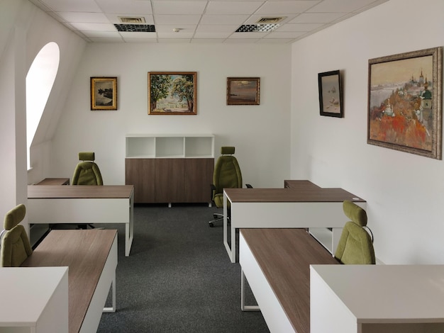 Ein leerer großer Büroraum mit Tischen, Stühlen und Bildern an den Wänden