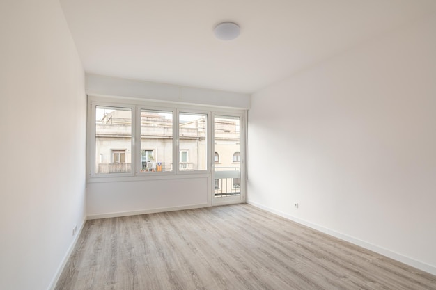 Ein leerer heller Raum mit grauem Holzparkett und weißen Wänden lässt den Raum optisch noch größer wirken