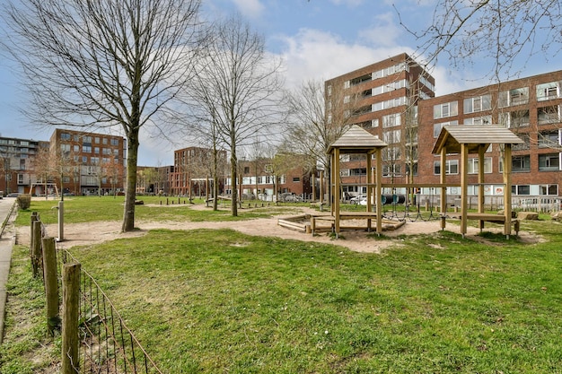 ein leerer Park mit Gebäuden im Hintergrund und grünem Gras auf dem Boden auf der linken Seite gibt es einen Spielplatz für Kinder