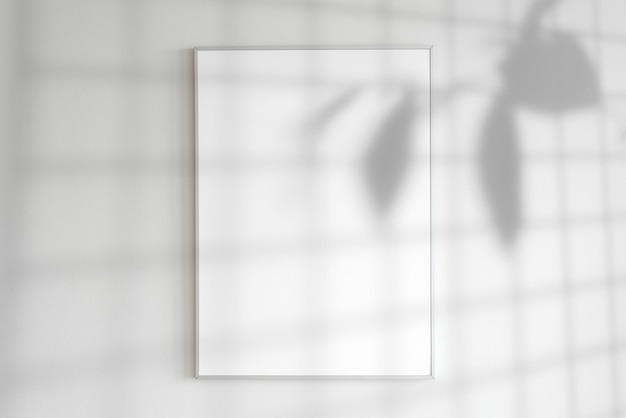Ein leerer Rahmen an einer Wand mit Pflanzenschatten