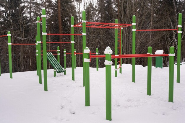 Ein leerer Spielplatz mit Metallstangen in einem Winterwald für Kinder und Erwachsene. Nutzen für die Gesundheit