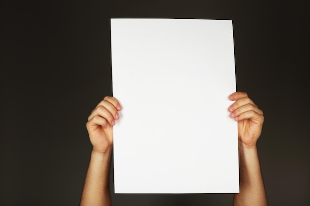 Ein leeres Blatt Papier in männlichen Händen auf dunklem Hintergrund