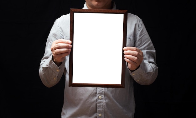 Foto ein leeres diplom oder ein mockup-zertifikat in der hand eines männlichen mitarbeiters, der ein hemd auf schwarzem hintergrund trägt der vertikale bildrahmen ist leer und der kopierplatzx9