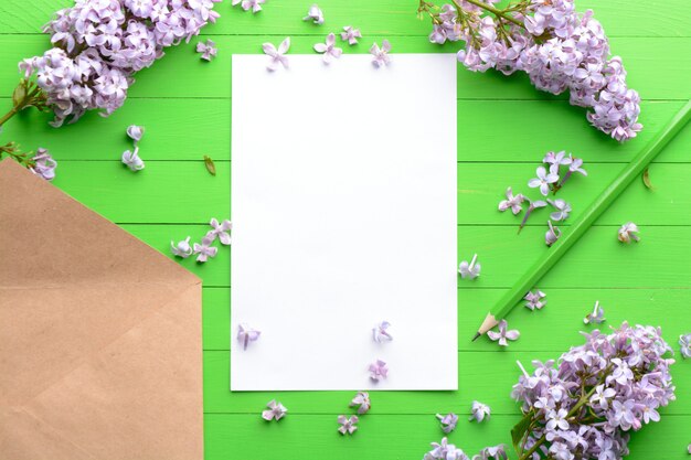 Ein leeres Stück Papier mit einem Umschlag auf grünem hölzernem Hintergrund