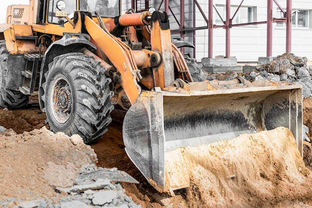 Ein leistungsstarker Frontlader auf der Baustelle übernimmt das Schleifen. Boden mit Baumaschinen bewegen. Ausgrabung.