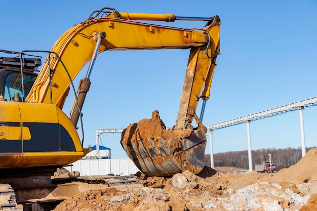 Foto ein leistungsstarker raupenbagger gräbt den boden gegen den blauen himmel erdarbeiten mit schwerem gerät auf der baustelle