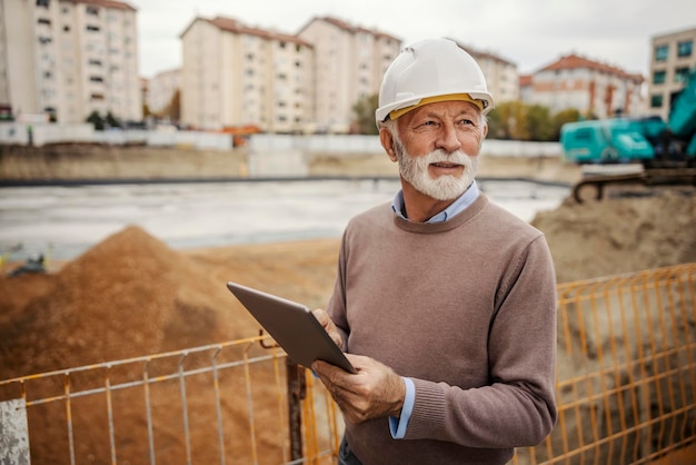 Ein leitender Architekt besucht die Baustelle und nutzt ein Tablet