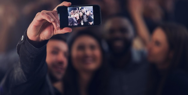 Ein letztes Selfie für das Jahr Schnappschuss einer Gruppe junger Freunde, die Selfies machen, während sie gemeinsam in einem Nachtclub tanzen