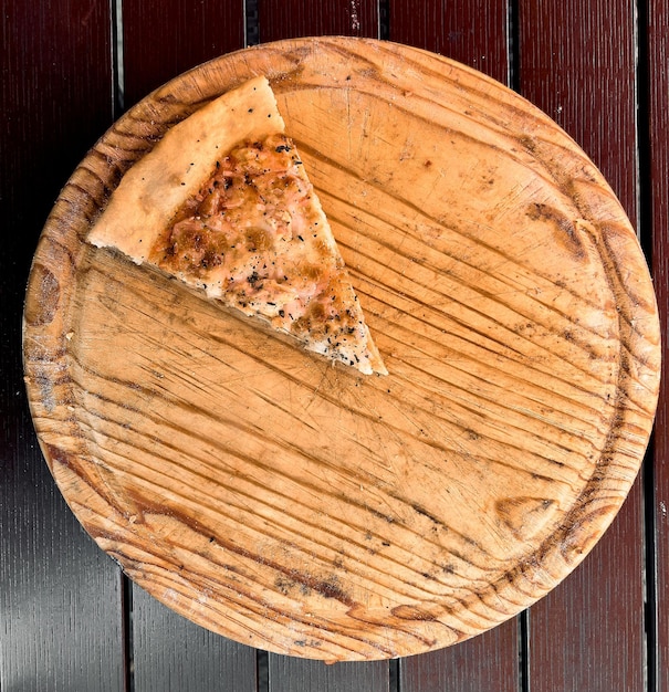Ein letztes Stück Pizza auf einem Holztablett