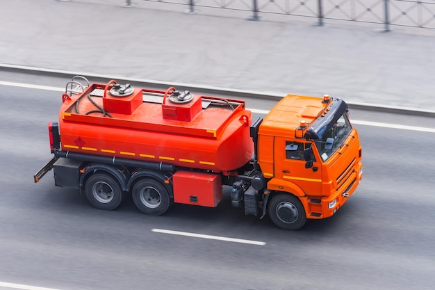 Ein leuchtend orangefarbener Lastwagen mit einem Tank für brennbaren Kraftstoff und andere brennbare Flüssigkeiten fährt die Autobahn entlang
