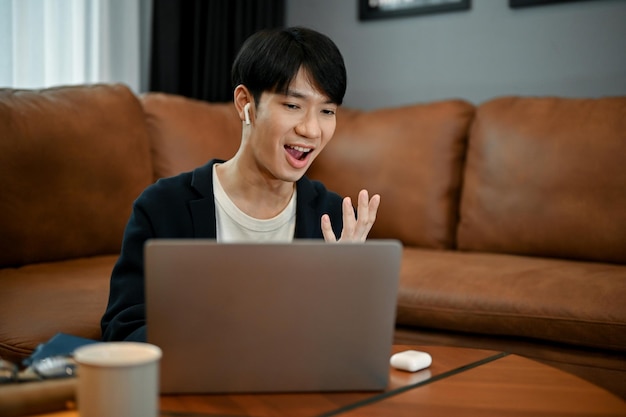 Ein liebenswerter junger asiatischer Mann, der mit seiner Familie auf einem Laptop telefoniert