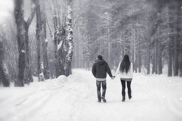 Ein Liebespaar auf einem Winterspaziergang. Mann und Frau bei einem Date im Park im Winter. Freunde in einem Winterpark