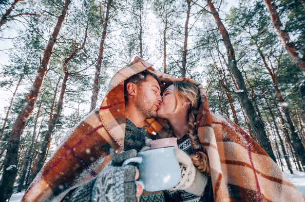 Ein liebevolles junges Paar ruht in den Bergen in einem schneebedeckten Wald. Konzept der gemeinsamen Ruhe