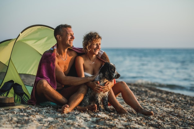 Ein liebevolles junges Paar verbringt den Tag am Strand mit seinem süßen Cocker Spaniel-Hund.