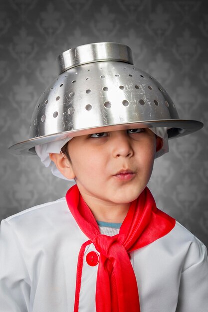 Ein lustiger kleiner Junge kocht in Uniform über Vintage-Hintergrund