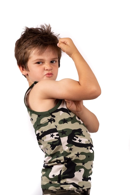 Foto ein lustiger zottiger junge in einem bunten khaki-t-shirt und shorts zeigt bizepsmuskeln ein starkes kind