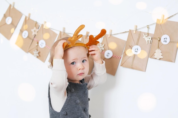 Ein lustiges Baby sitzt in der Nähe eines handgefertigten Adventskalenders Vorbereitung auf Weihnachten Bastelumschläge