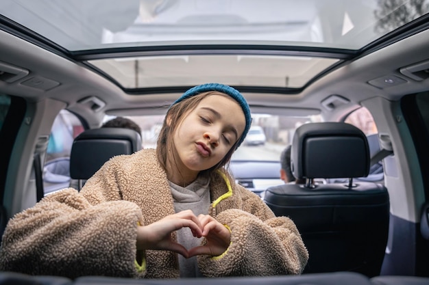 Ein lustiges kleines Mädchen posiert auf dem Rücksitz eines Autos und spielt im Auto