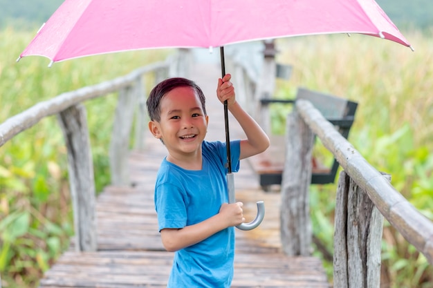 Ein lustiges Spielen des Jungen mit Regenschirm