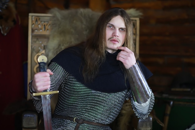 Ein mächtiger Held mit langen Haaren in Kettenhemdrüstung in einer alten Halle. Mittelalterlicher Krieger in den Kammern des Ritters.
