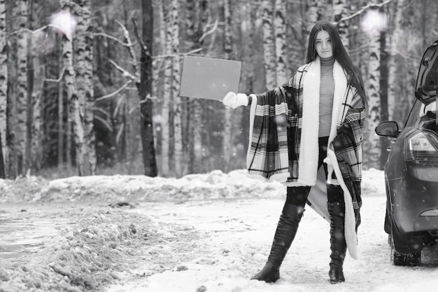 Ein Mädchen an einem bewölkten Wintertag mit schneebedeckten Feldern und Wäldern
