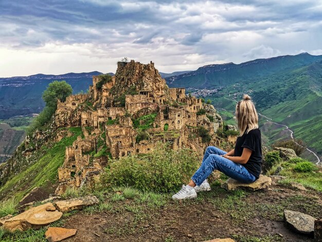 Ein Mädchen auf dem Hintergrund des Dorfes Gamsutl im Kaukasus auf einer Klippe Dagestan Russland Juni 2021