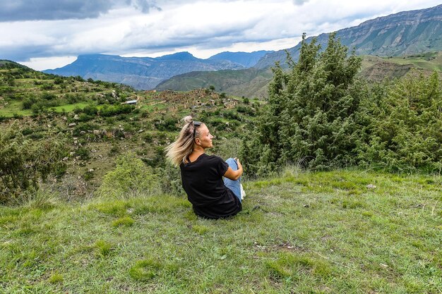 Ein Mädchen auf dem Hintergrund des Dorfes Kurib im Kaukasus auf einer Klippe Dagestan Russland Juni 2021