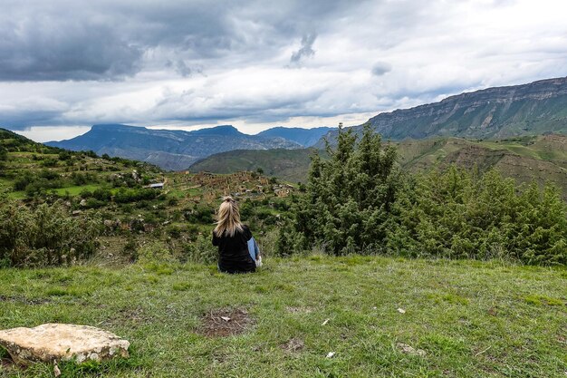 Ein Mädchen auf dem Hintergrund des Dorfes Kurib im Kaukasus auf einer Klippe Dagestan Russland Juni 2021