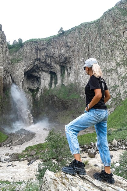 Ein Mädchen auf dem Hintergrund des Wasserfalls KarakayaSu auf dem Territorium von KabardinoBalkarien
