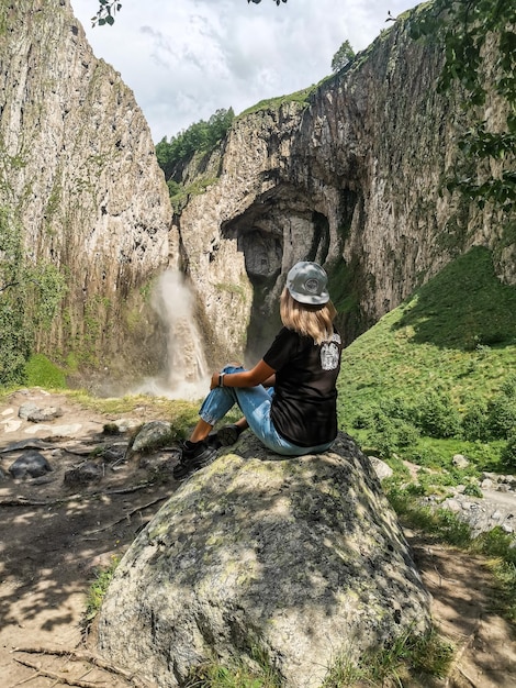 Ein Mädchen auf dem Hintergrund des Wasserfalls TuzlukShapa auf dem Territorium von KabardinoBalkarien Kaukasus Russland