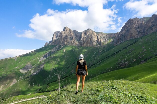Ein Mädchen auf dem Hintergrund einer grünen Landschaft des Aktoprak-Passes im Kaukasus Russland Juni 2021