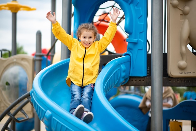 Ein Mädchen auf dem Spielplatz Sie auf der Rutsche und hat eine lustige Kindheitszeit mit der Familie