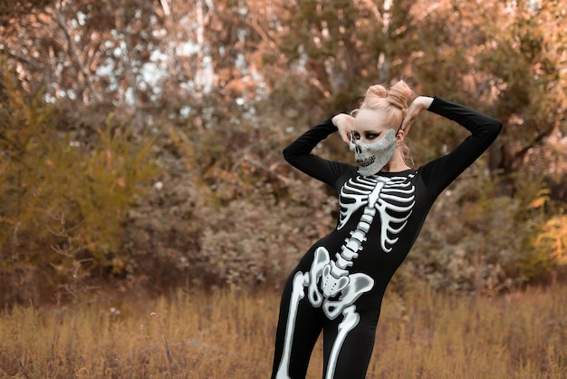 Ein Mädchen, das als Skelett verkleidet ist und eine Maske mit Strasssteinen trägt, sieht an Halloween einschüchternd aus