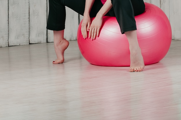 Ein Mädchen, das auf einem rosa fitball in einer Turnhalle, heller Hintergrund sitzt