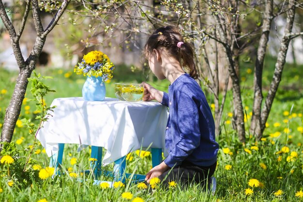 Ein Mädchen, das draußen im Frühlingsgarten Kräutertee trinkt, an einem sonnigen Tag.