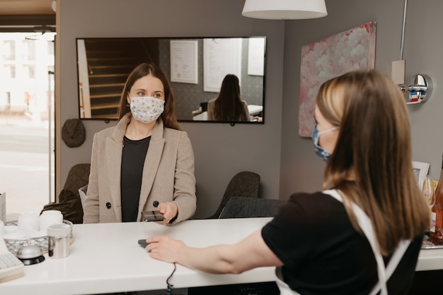 Ein Mädchen, das eine Gesichtsmaske trägt, bezahlt mit einem Handy kontaktlos