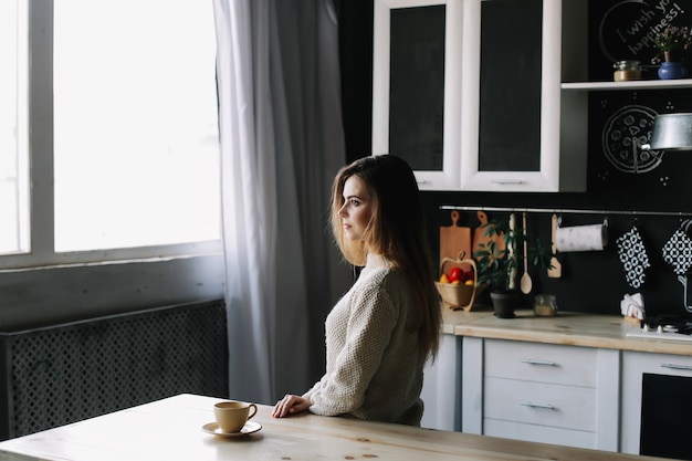 ein Mädchen, das morgens zu Hause Kaffee in der Küche trinkt