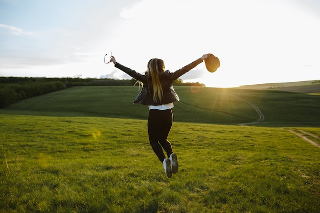 Ein Mädchen, das oben mit Freude am Sonnenuntergang springt