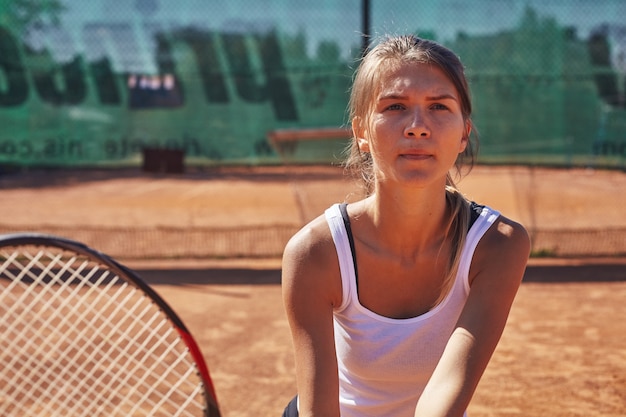 Ein Mädchen, das Tennis auf dem Platz an einem schönen sonnigen Tag spielt