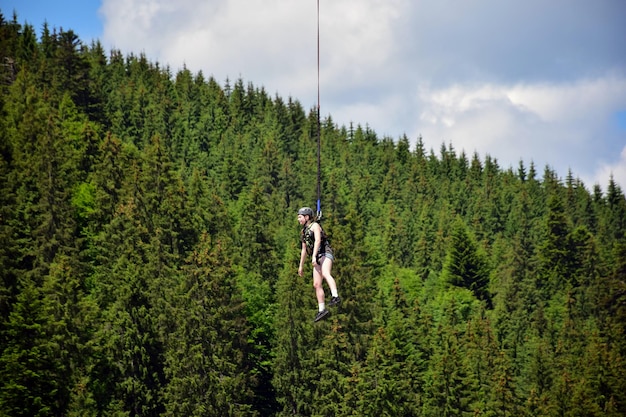 Ein Mädchen, das von einer Bungee-Jumping-Fahrt gesprungen ist, hängt an einem engen Seil in großer Höhe
