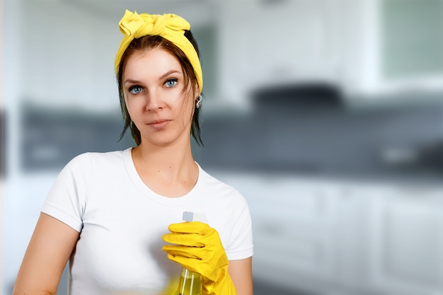 Ein Mädchen eine Putzfrau mit tragenden Handschuhen eines Reinigers und einem Lappen auf einem blauen Hintergrund