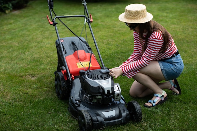 Ein Mädchen entfernt die Batterie von einem Rasenmäher im Garten