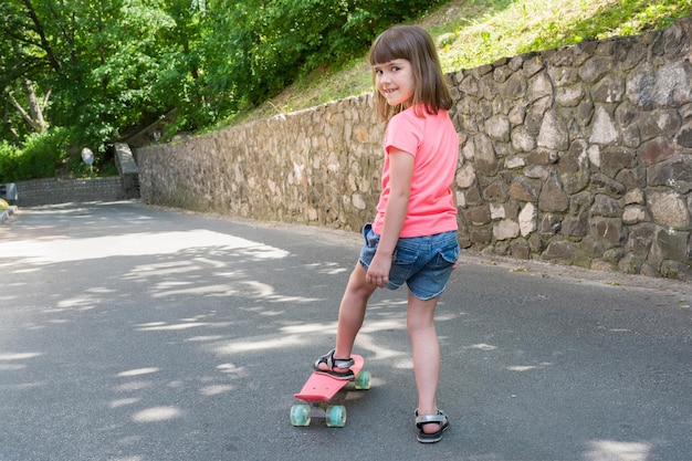 Ein Mädchen fährt im Park Skateboard. Ein kleines Kind posiert vor einer Kamera