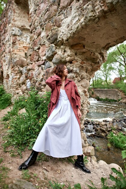 Ein Mädchen gegenüber einem alten zerstörten Gebäude nahe einem stürmischen Fluss