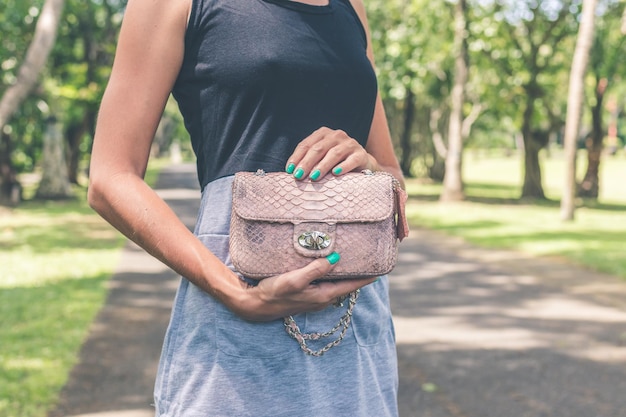 Foto ein mädchen geht im park mit einer tasche aus pythonhaut in den händen