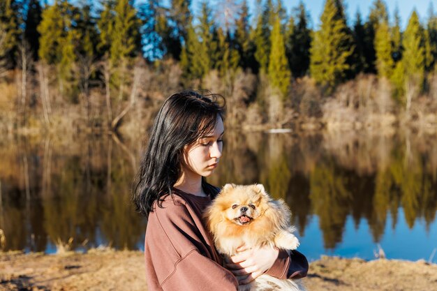 Ein Mädchen geht mit einem Hund im Park im Freien mit einem Haustier spazieren, ein Porträt mit einem kleinen Welpen