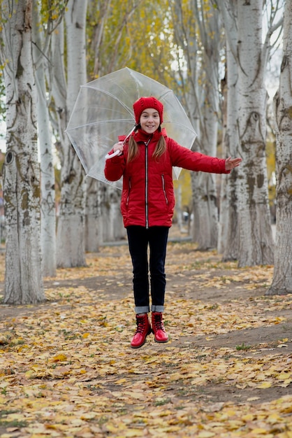 Ein Mädchen geht und spielt mit einem durchsichtigen Regenschirm im Park Autumn Atmother